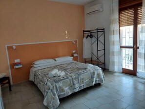 A bedroom with a bed, a bedside table, a hanging rack, and a window with a view. - Mosaico (POMPEI)