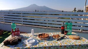 A table with food and drinks on a balcony with a mountain view. - Mosaico (Pompei)