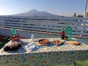 A table with food and drinks on a balcony with a mountain view. - Mosaico (Pompei)