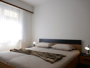 Une chambre à coucher avec un lit, des lampes de chevet, une fenêtre avec des rideaux et une table de chevet.