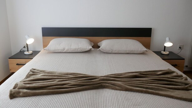 A bed with a headboard, two bedside tables with lamps, and a blanket on the bed. - Beautiful apartment for 5 guests with WIFI, TV and patio (Lodrino)