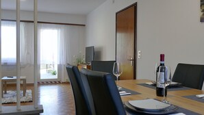 A dining area with a wooden table, black chairs, a TV, and a door. - Beautiful apartment for 5 guests with WIFI, TV and patio (Lodrino)