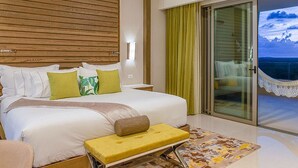 A hotel room with a large bed, a bedside table, a chair, a small table, and a view of the sea through a sliding glass door. - Salt Air in Cancun (Cancún)