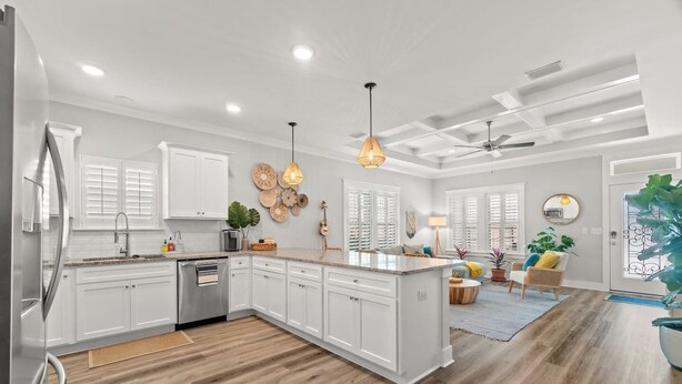 A modern kitchen with white cabinets, a built-in island, wooden flooring, pendant lighting, and a ceiling fan. - Walk to Beach, Golf Cart Included, Near Rosemary (Panama City Beach)