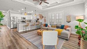 A spacious living area with a sofa, coffee table, and a kitchen in the background. - Walk to Beach, Golf Cart Included, Near Rosemary (Panama City Beach)
