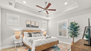 A bedroom with a bed, bedside tables, a ceiling fan, and a large window. - Walk to Beach, Golf Cart Included, Near Rosemary (Panama City Beach)