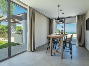 Ein moderner Essbereich mit großem Tisch, Stühlen und Blick ins Freie.