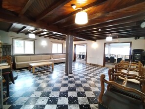 Ein Zimmer mit Schachbrettmuster Boden, Holzbalken, einer Couch, einem Tisch und einem Stuhl.