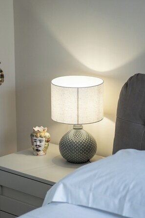 Ein Nachttisch mit einer Lampe, einer Dekoration und einem Kissen.
