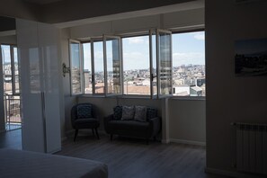 Una habitación con un ventanal grande, un sofá, una silla y una cama.