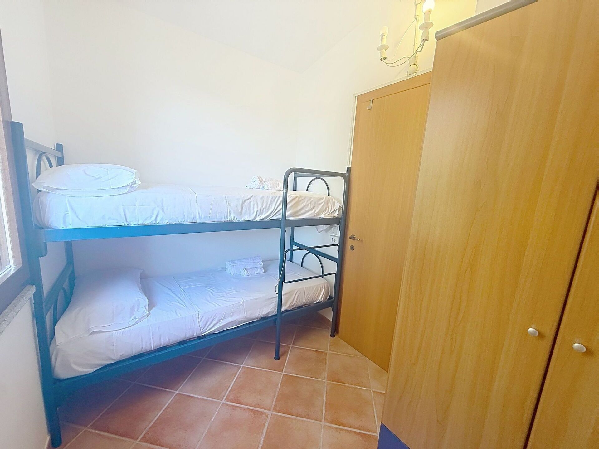 A bunk bed room with a wardrobe and a window.