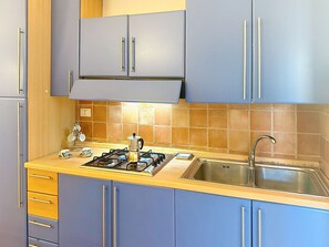 A kitchen with blue cabinets, a gas stove, a sink, and a coffee maker. - Wonderful private villa for 8 people with WIFI, A/C, TV, terrace and pets allowed (Villasimius)