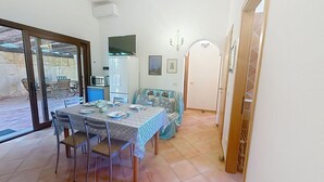 Un comedor con una mesa preparada para cuatro personas, un sofá, un microondas y un refrigerador.