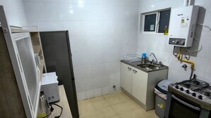 Una cocina compacta con estufa a gas, lavamanos y microondas.