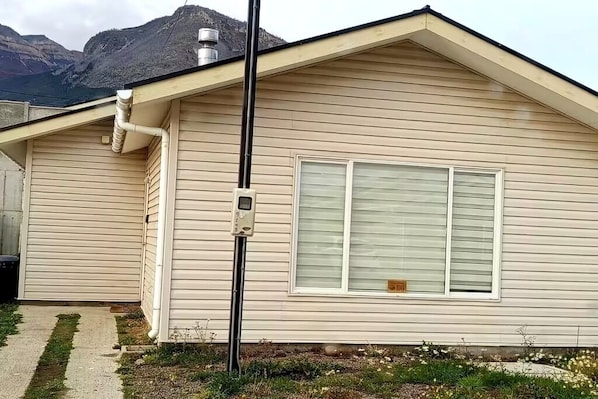 A house with a chimney, a window with a plate, and a metal pole.