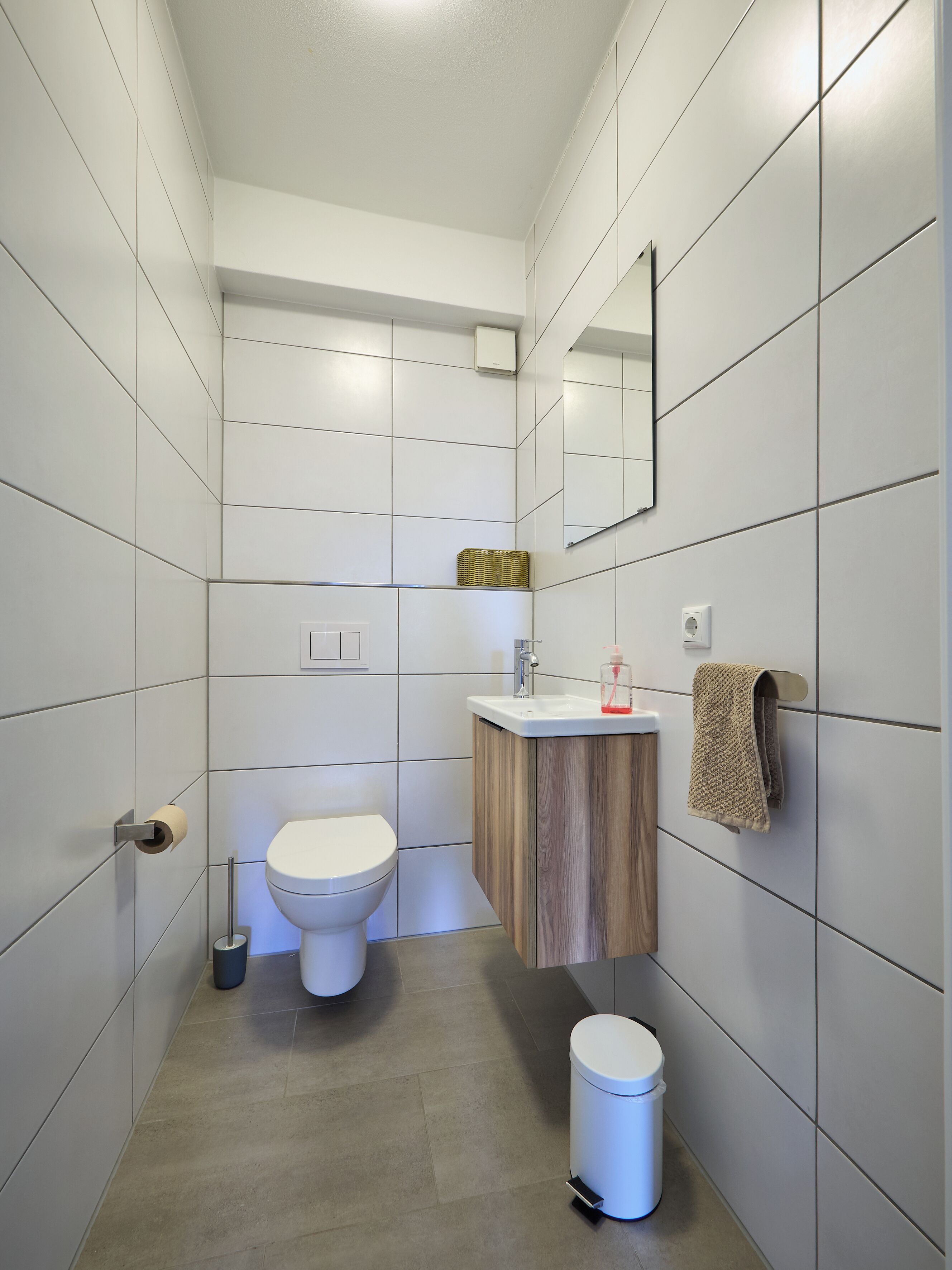 A modern bathroom with a toilet, sink, and mirror.