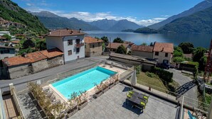 Ein Wohngebiet mit einem Schwimmbad, Häusern mit roten Ziegeldächern und Bergen im Hintergrund.