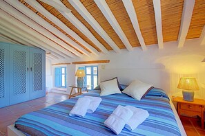 Una camera da letto con un letto, cuscini, un comodino, una lampada e un armadio.