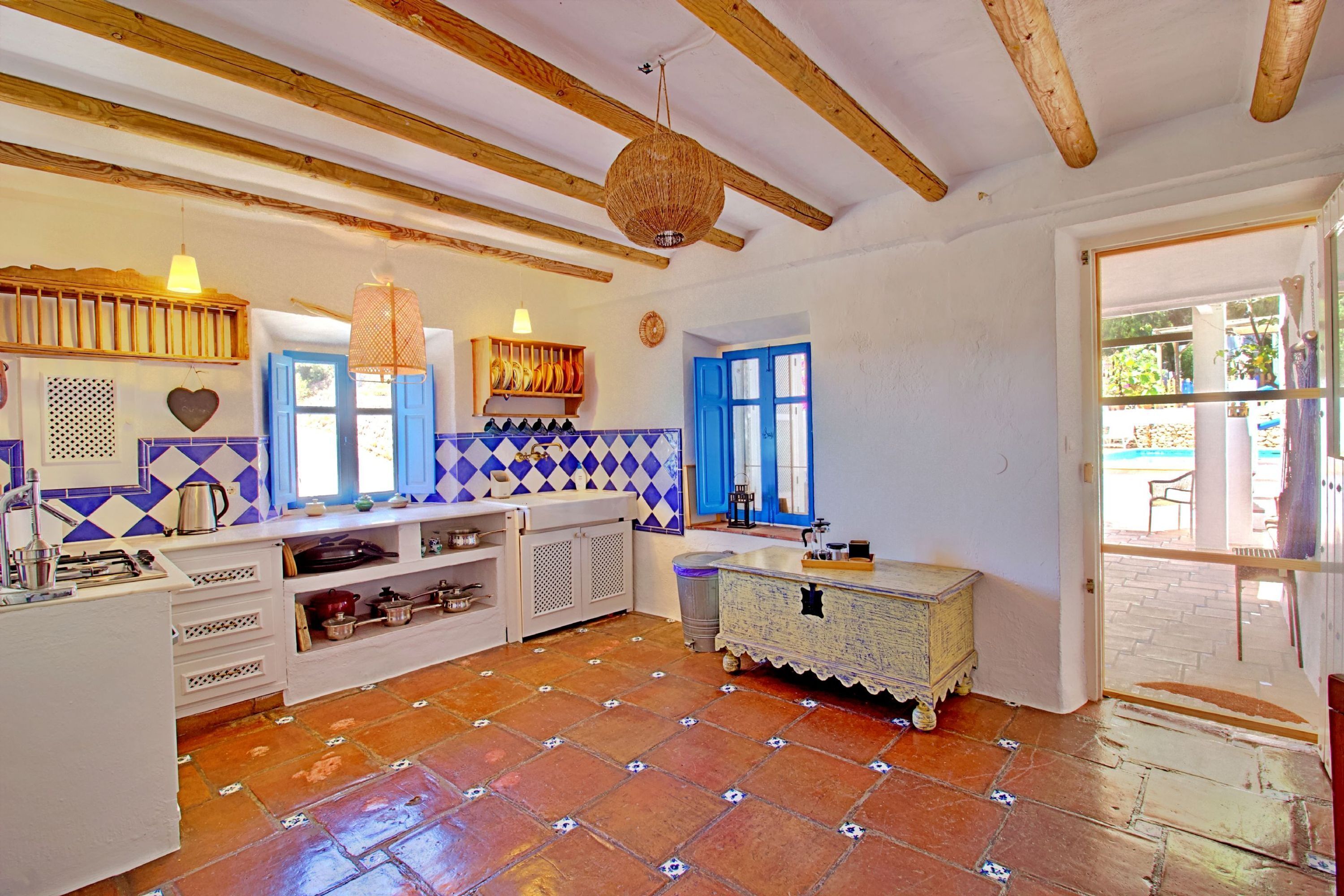 A kitchen with wooden beams, a tiled backsplash, and a rustic wooden cabinet.