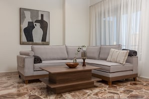 Een moderne woonkamer met een modulaire bank, een houten salontafel en een vloer met een marmerlook.