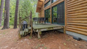 A log cabin with a deck, outdoor seating, and a staircase leading to the entrance. - Walk to Elk Rapids + Steps from East GT Bay (Elk Rapids)