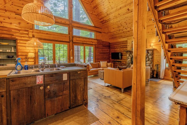 A log cabin interior with a kitchen island, sofa, and fireplace.