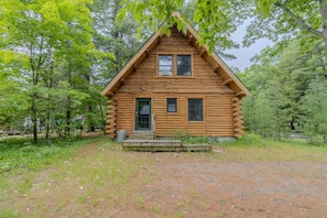 A log cabin with a front porch, two windows, and a door.