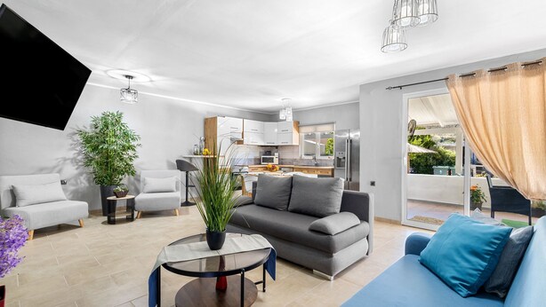 Ein modernes Wohnzimmer mit einer Couch, einem Couchtisch und einem Flachbildfernseher.