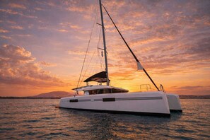 Eine weiße Yacht mit Kabine und Segel, bei Sonnenuntergang im Hafen.