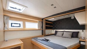 Quarto compacto e moderno com cama, estantes embutidas, secretária e janela.