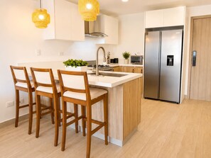 A modern kitchen with a central island, stainless steel appliances, and wooden chairs. - ®2BR{Crystal~Lagoon~Retreat} PuntaCana +Prive Pool (Punta Cana)
