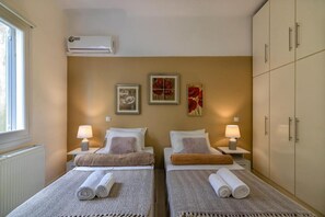 Ein Hotelzimmer mit zwei Betten, einem Heizkörper, einer Klimaanlage und Bildern an der Wand.