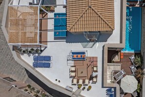 Ein Poolbereich auf dem Dach mit überdachter Lounge, Liegestuhl und Sonnenschirm.