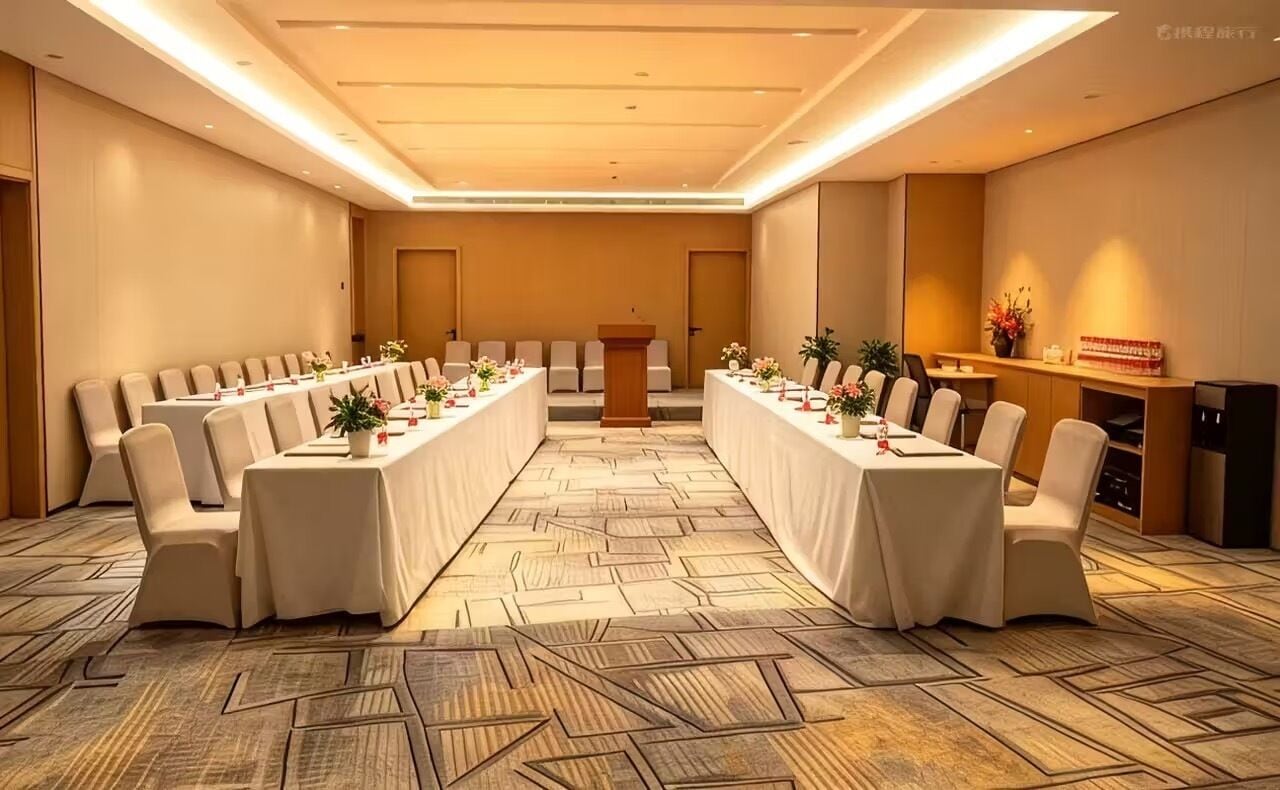 A conference room with a long table, chairs, a podium, and a reception desk.