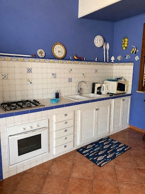 Eine Küche mit Gasherd, Backofen, Spüle und Mikrowelle.