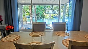 Un comedor con mesa y sillas, vista a una piscina y una casa al fondo.