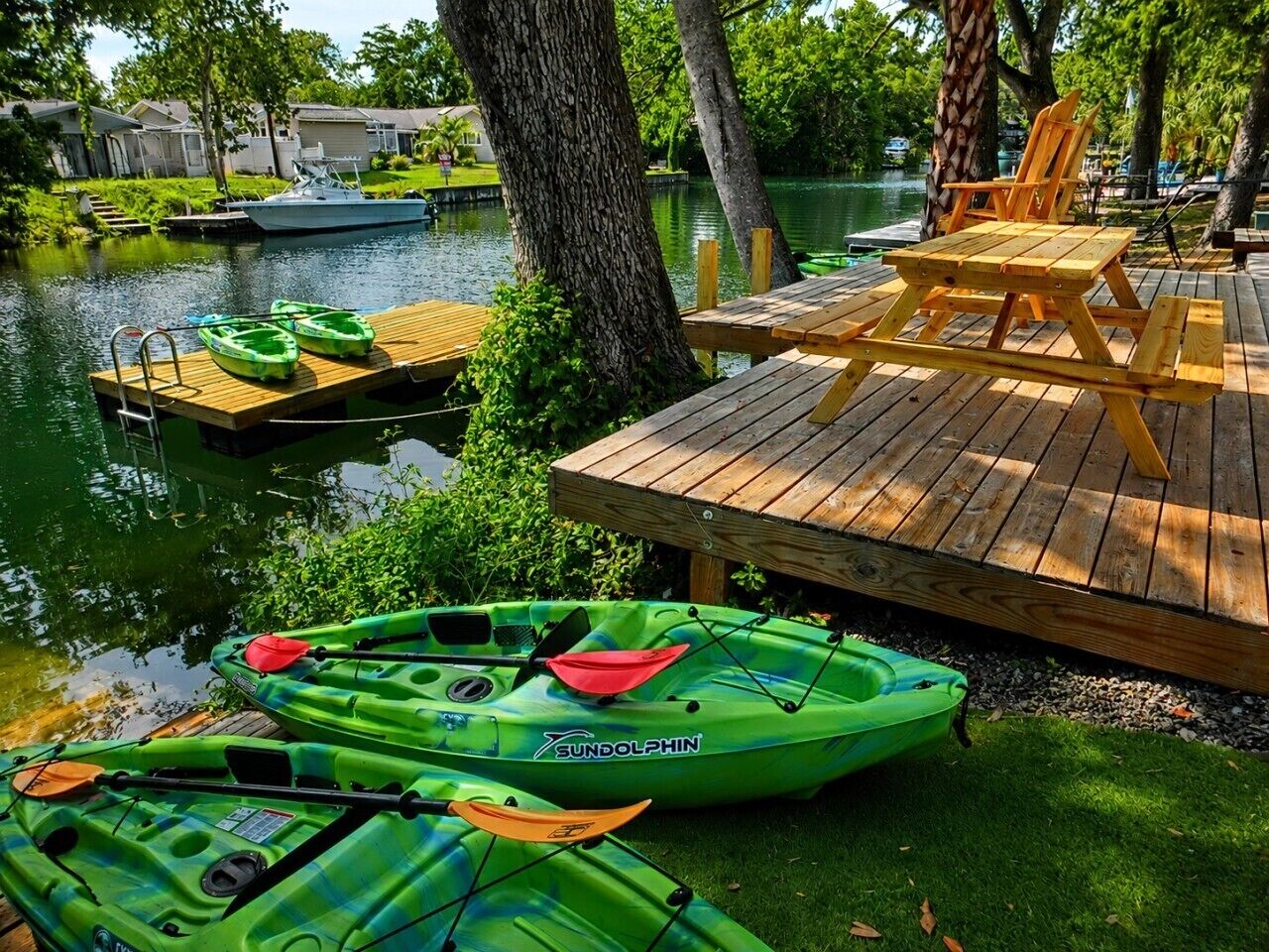 Une jetée en bois avec des kayaks, une planche de paddle et une chaise.