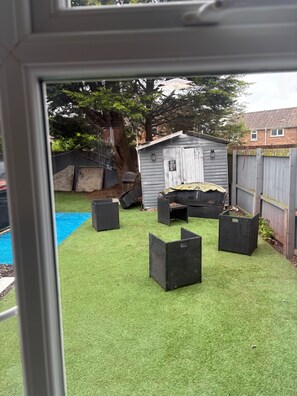 A backyard with artificial grass, a shed, and outdoor furniture. - House Sleeps 6 With Hot Tub and Parkingcheaiesst Than on any Site (Blackpool)