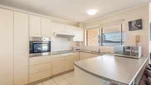 Una cocina moderna con armarios blancos, horno empotrado, microondas y un amplio ventanal con vistas.