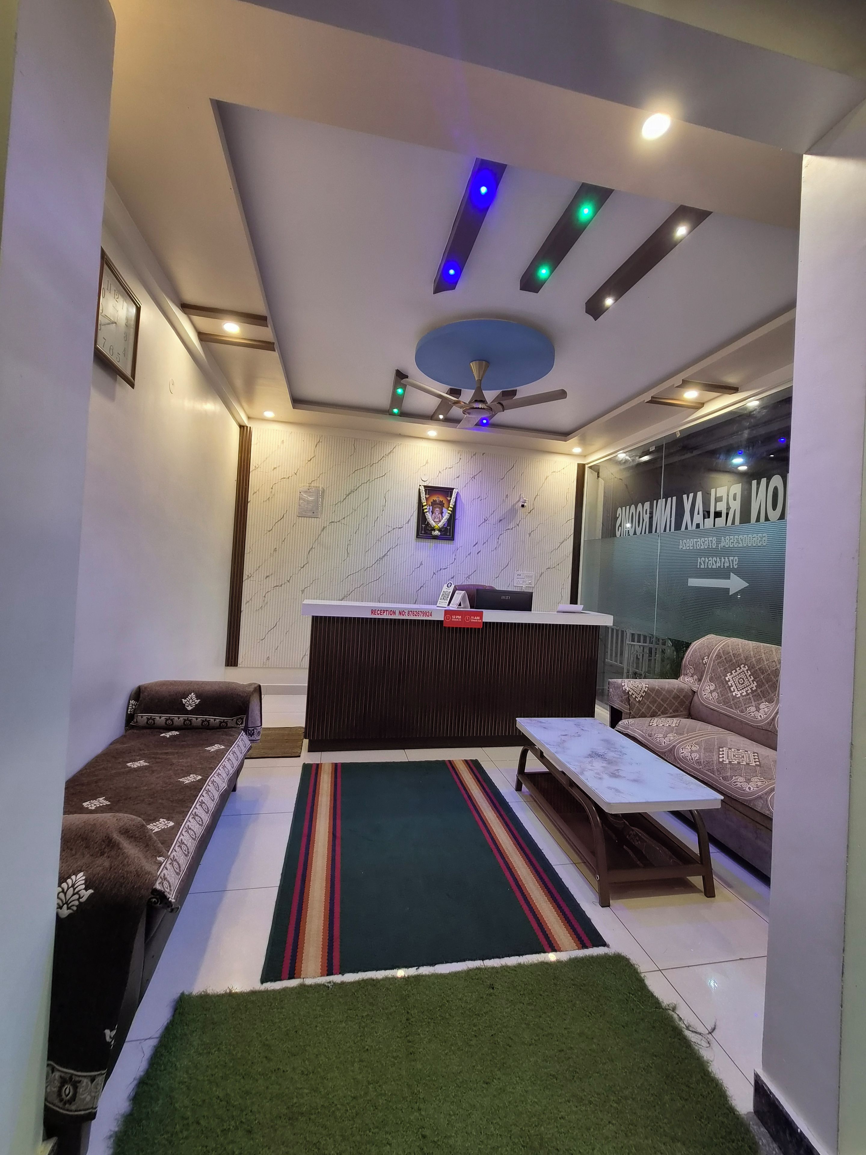 A reception area with a reception desk, a sofa, a small table, and a ceiling fan.