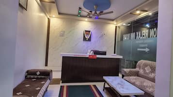 A reception area with a reception desk, a sofa, a small table, and a ceiling fan.