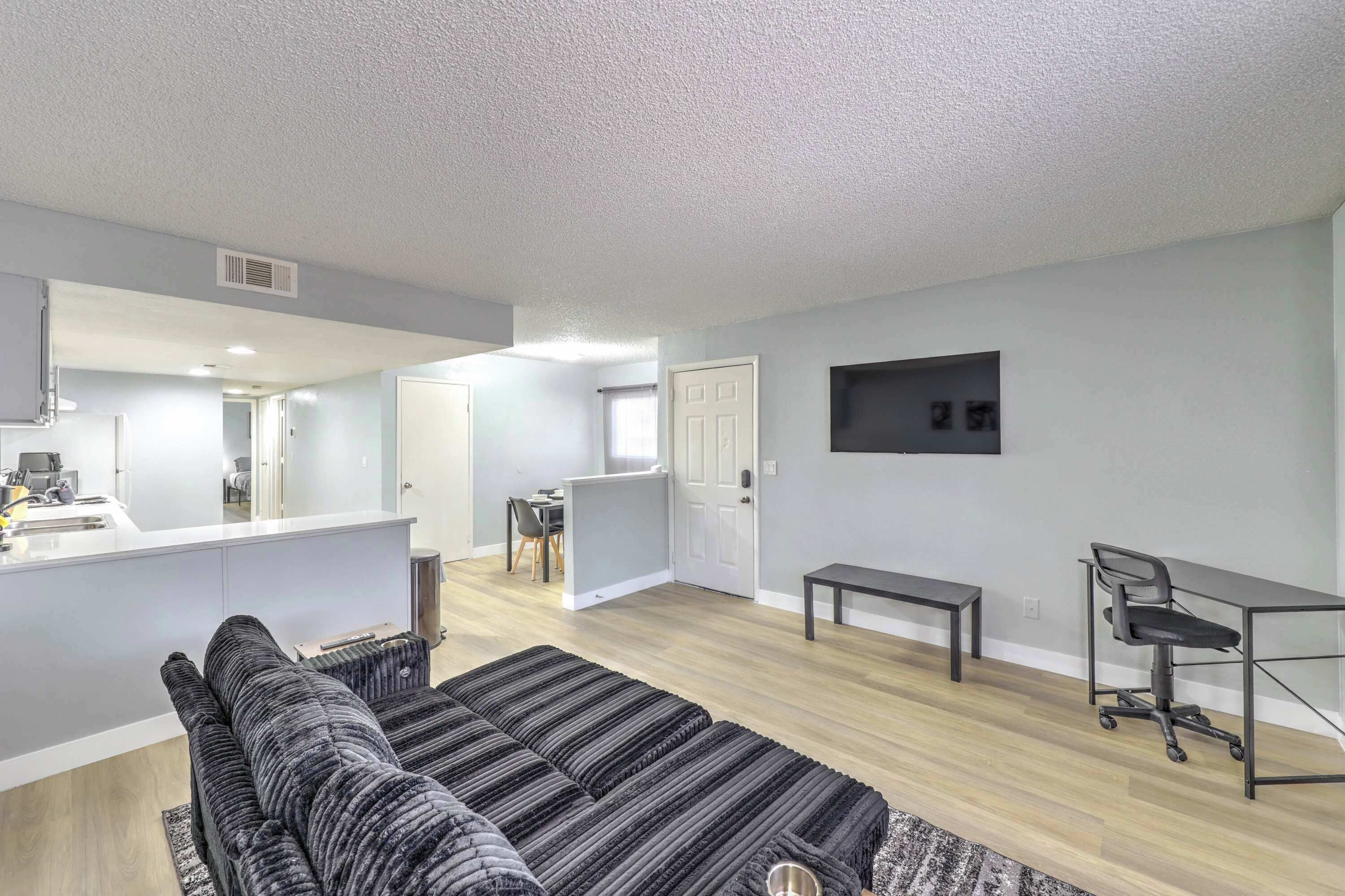 Un appartement moderne comprenant un canapé, un coin repas, une cuisine et un petit espace bureau.