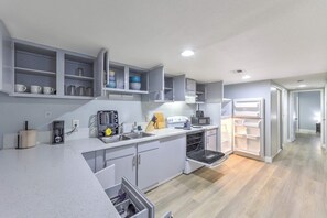 A modern kitchen with white cabinets, a built-in oven, a coffee maker, and a microwave. - Relax in Comfort! Sleeps 6! (Las Vegas)