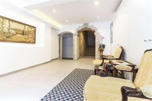 Un vaste espace de vie comprenant un canapé, un tapis à motifs, un tableau et un escalier menant à une autre piÚce.