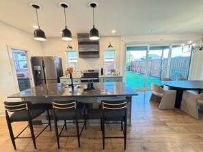 A modern kitchen with a large island, bar stools, and pendant lighting. - The Carriage House - 5 BEDROOMS / SLEEPS 16 / 1 MILE FROM ACU (Abilene)