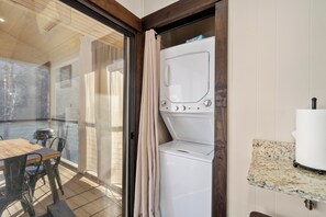 A room with a washing machine, a dining table with chairs, and a view through a glass door. - Family-friendly, waterfront, 2-bedroom condo inside Rumbling Bald, on Lake Lure (Lake Lure)