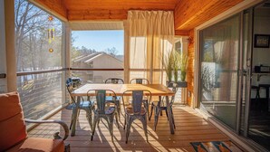Een houten terras met een tafel, stoelen, een schuifpui en uitzicht op een huis.