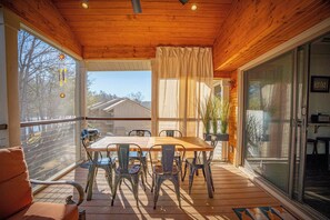 A wooden deck with a table and chairs, a sliding glass door, and a view of a house. - Family-friendly, waterfront, 2-bedroom condo inside Rumbling Bald, on Lake Lure (Lake Lure)