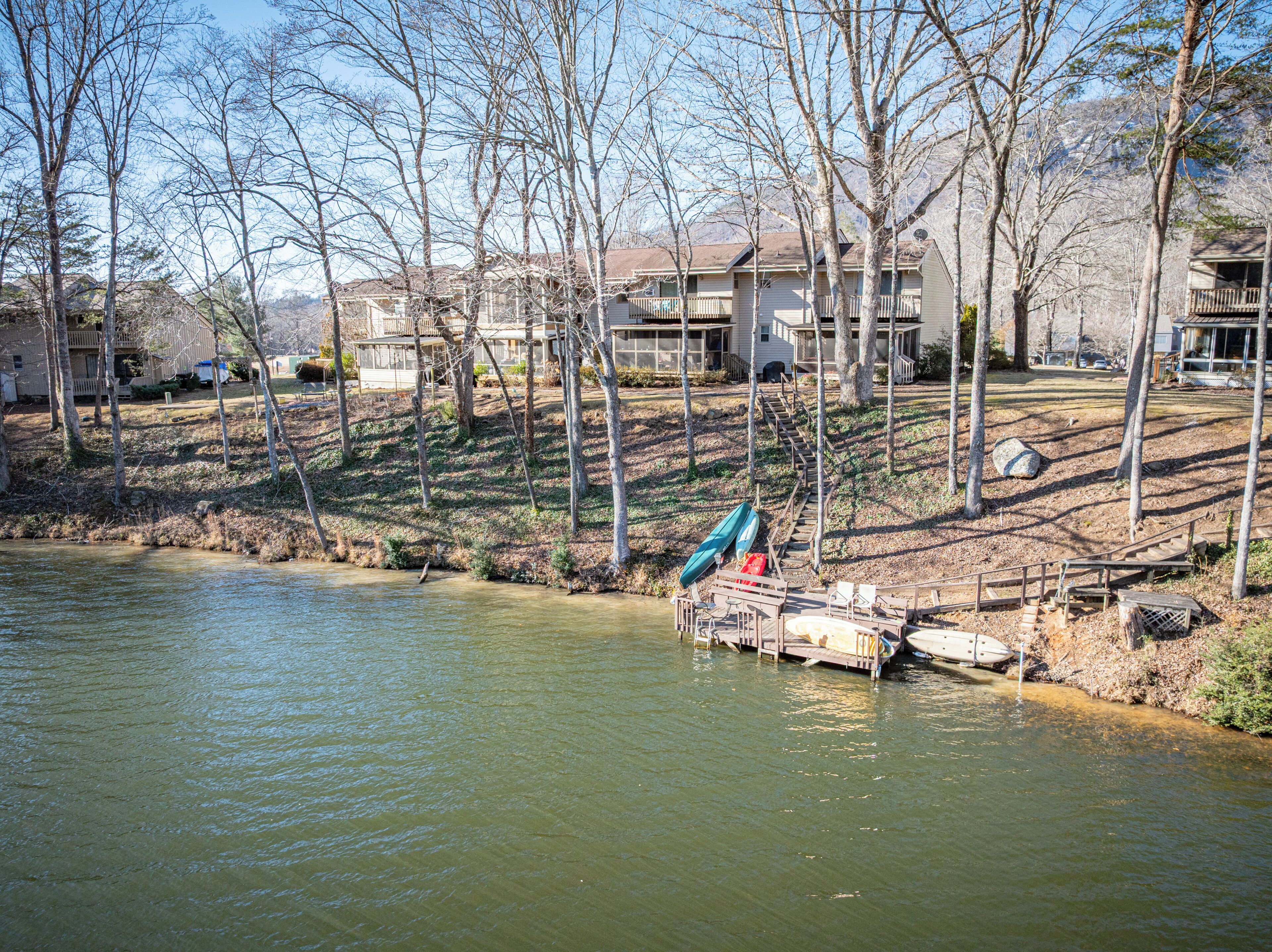 A lakeside property with a dock, boats, and a building with a porch.