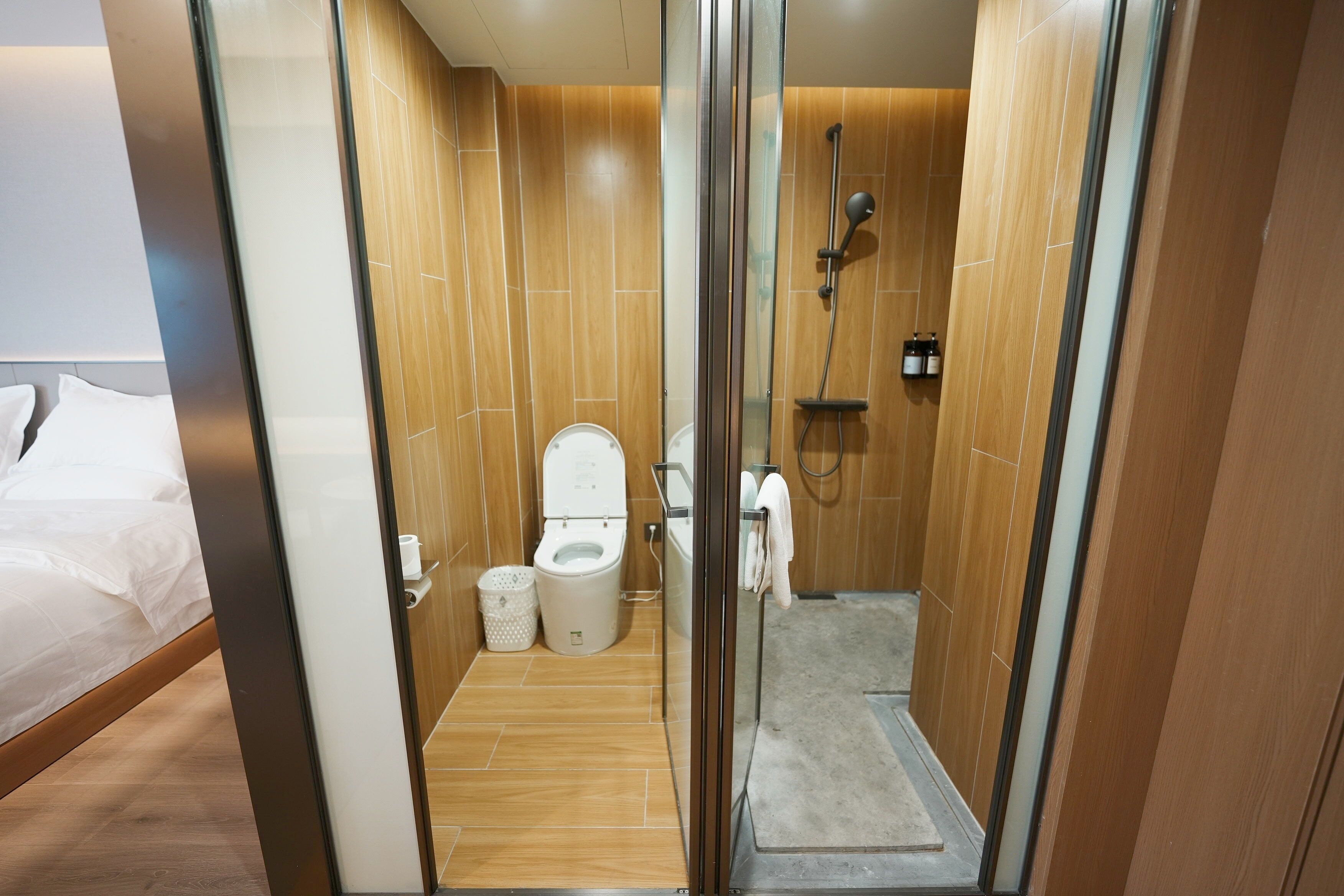 A modern bathroom with a glass shower enclosure, a toilet, and a bidet.